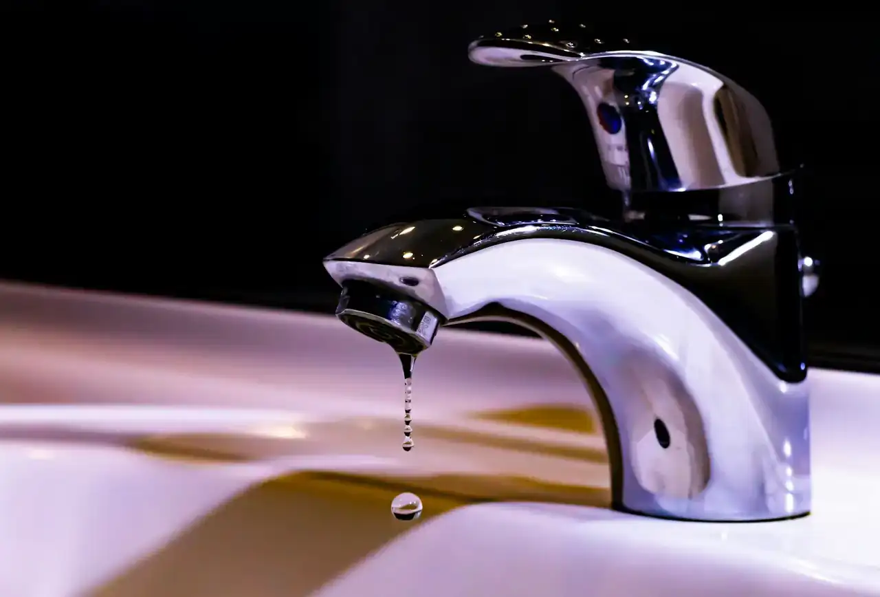 Chrome faucet with a drip falling from the spout