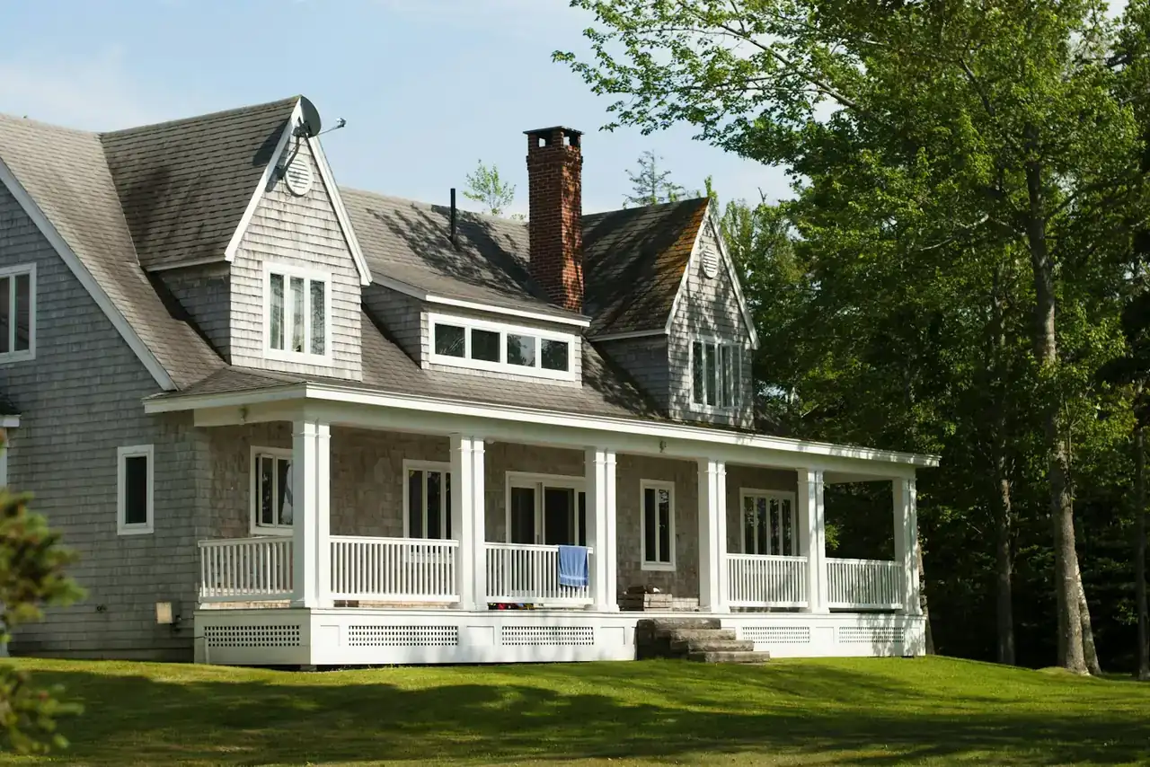 Shingled New England house with a wraparound porch