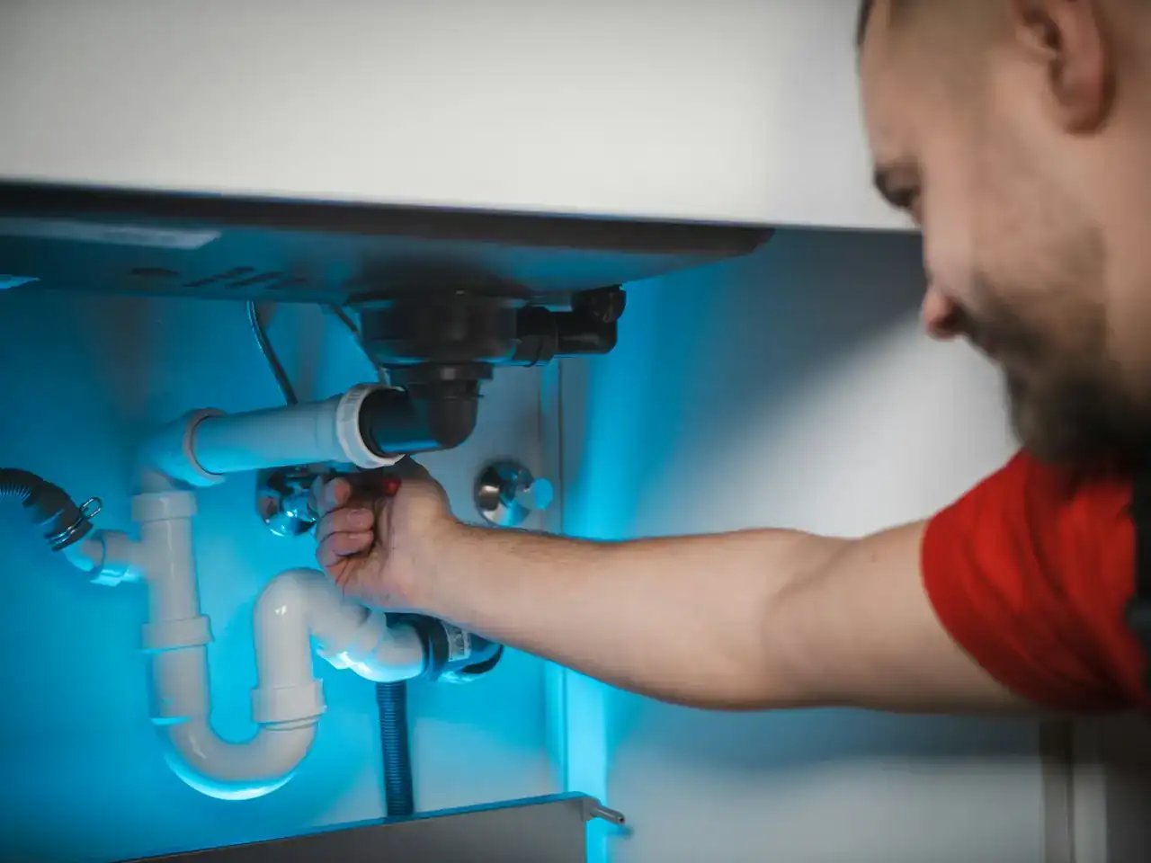 Plumber working on the drain pipes under a sink