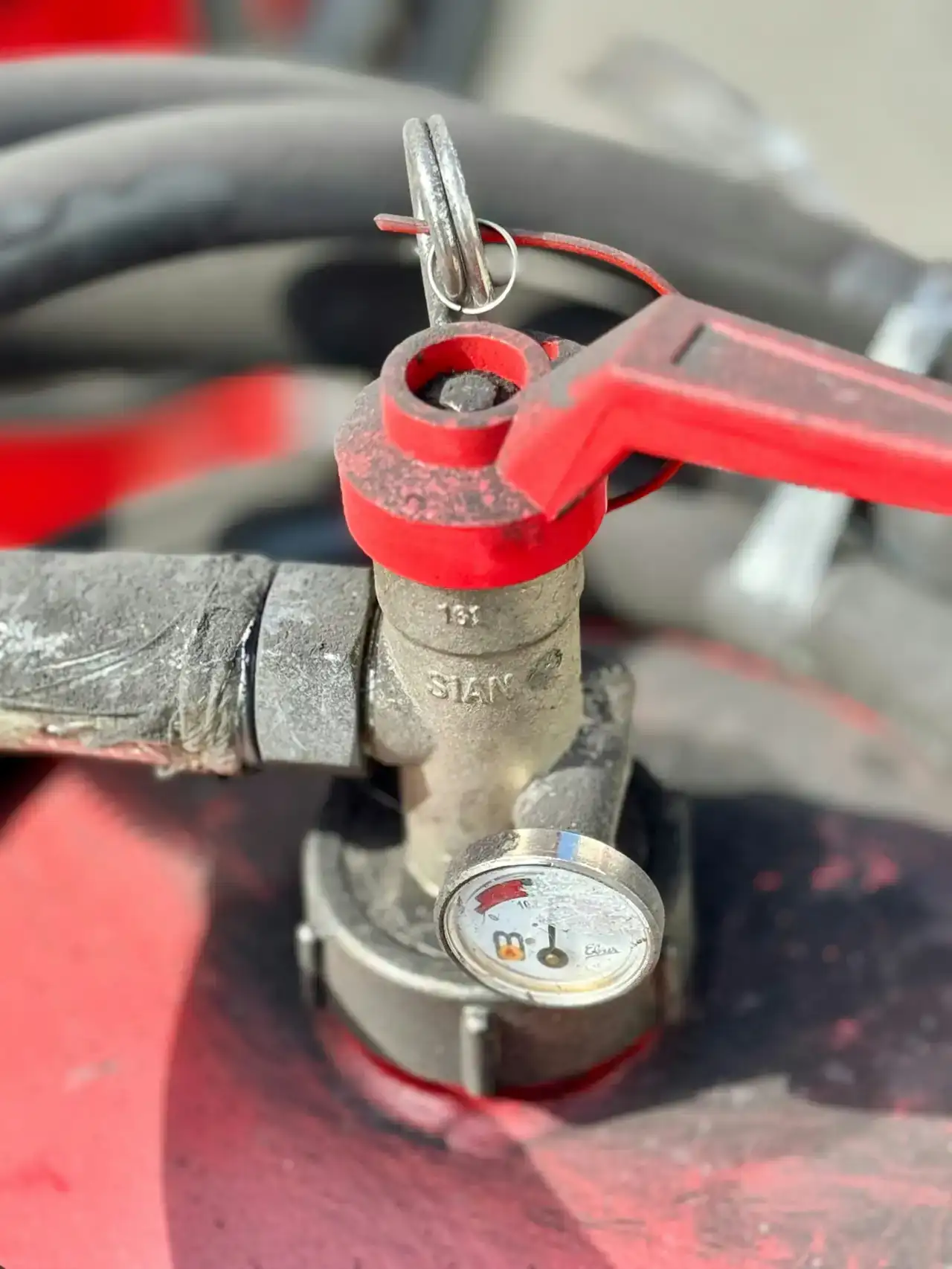 Red valve handle beside a pressure gauge